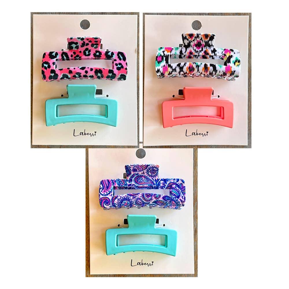 Three sets of rectangular hair clips with colorful animal print, coral, paisley, and turquoise designs on white cards